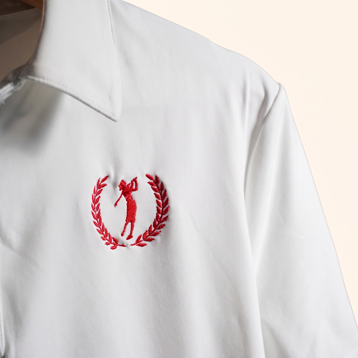 Detail of red laurel golfer crest embroidery on white polo